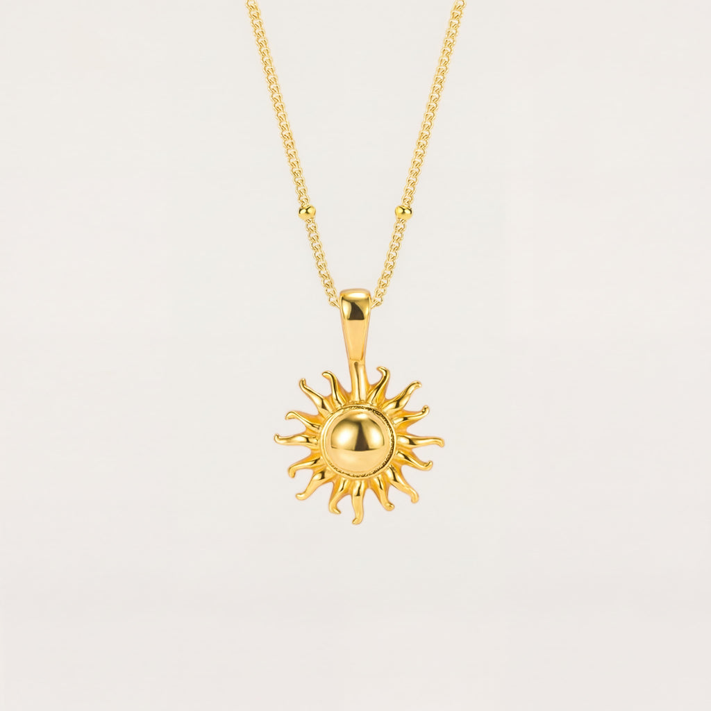 Gold sun-shaped pendant necklace on a light beige background